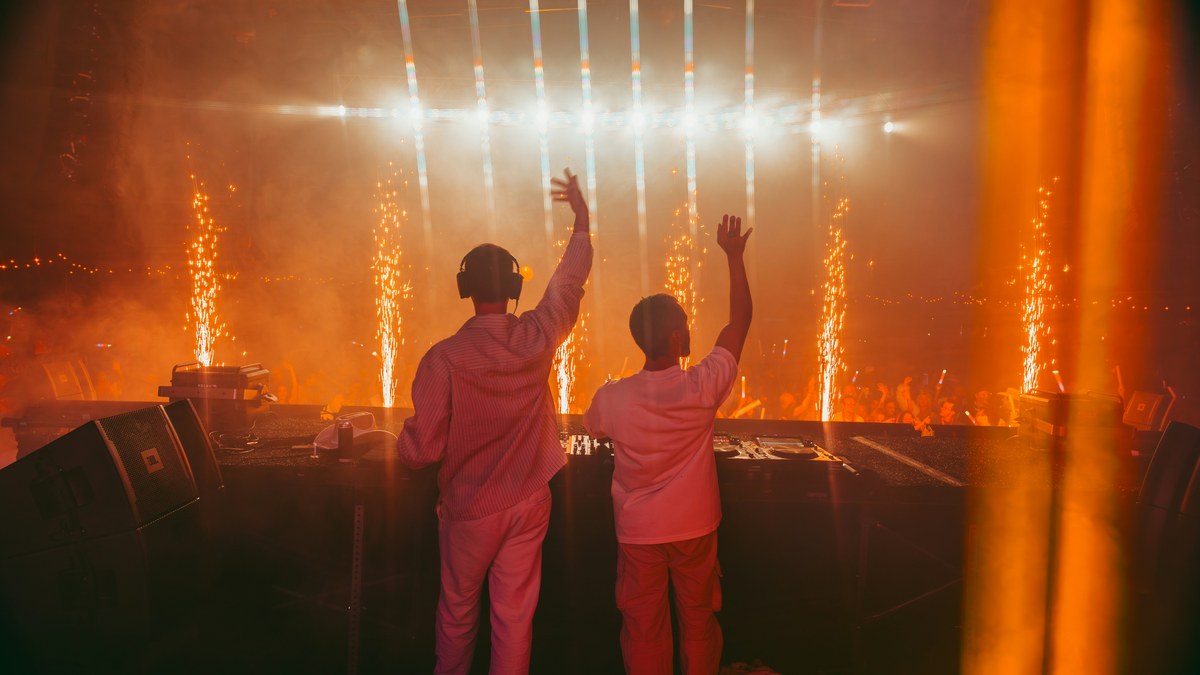 Two DJs at the decks with cold spark fountains erupting around them.