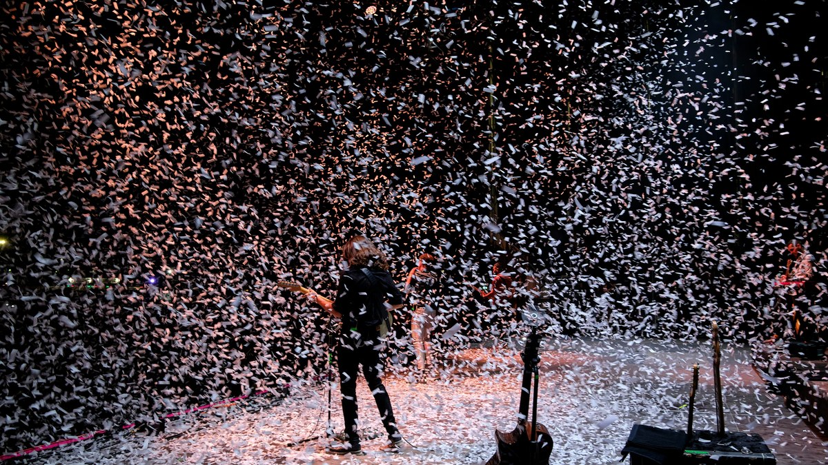 A confetti burst raining down over musicians on stage.