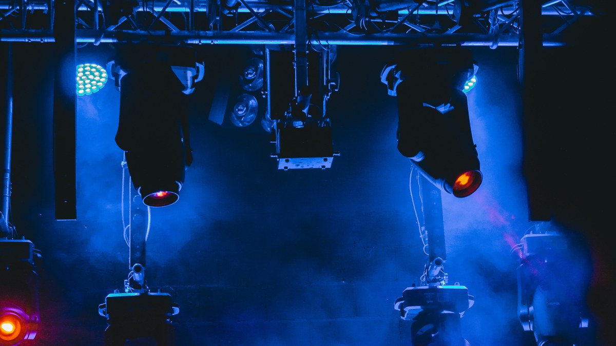 Moving head fixtures mounted on a truss glowing blue.