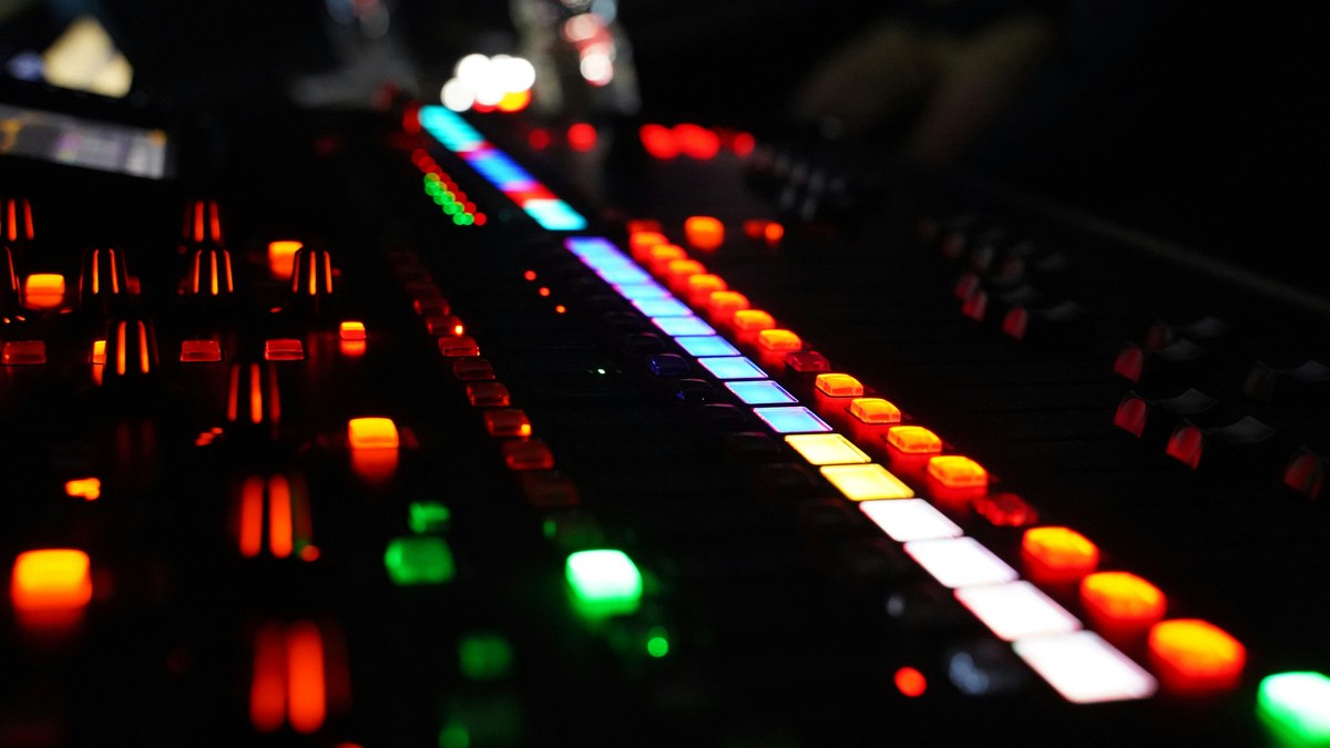 Close-up of a digital mixing console with glowing faders and buttons.