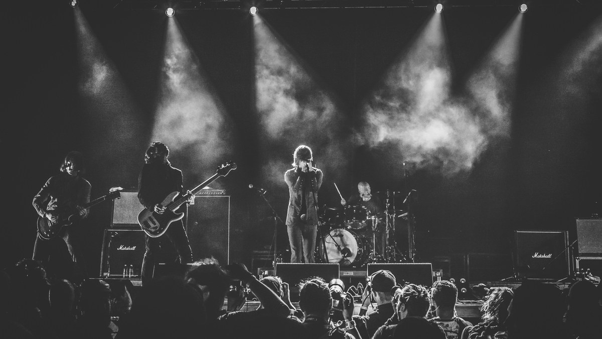 A band performing on stage under dramatic spotlights.