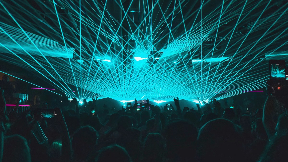 Turquoise laser beams sweeping over a concert crowd.