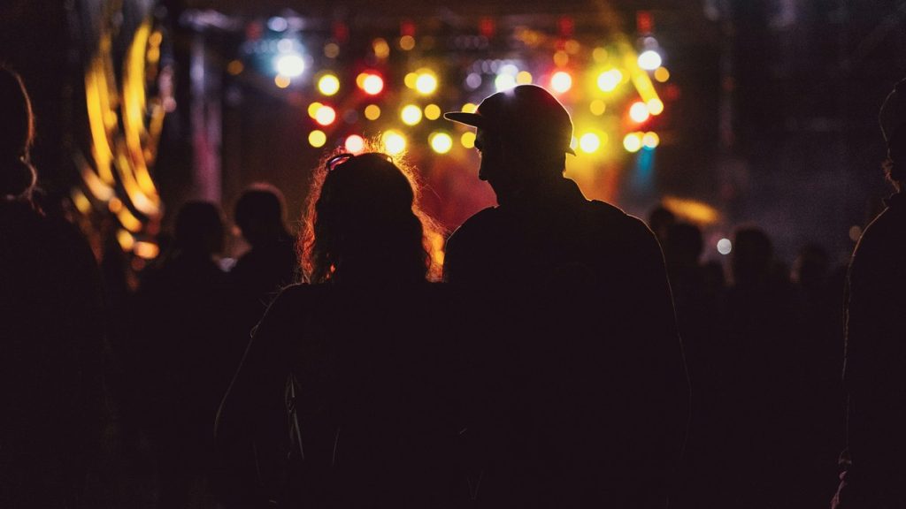Couple silhouetted against bright concert stage lights