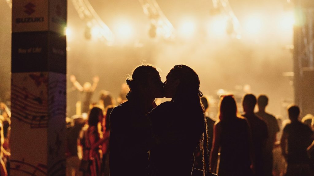 Couple kissing silhouetted against concert lights