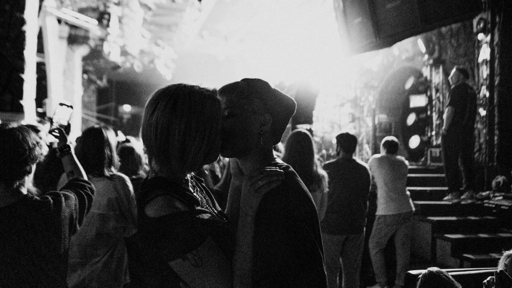 Couple kissing at a concert in black and white