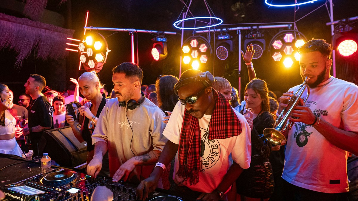 DJ booth with musicians and a lively crowd