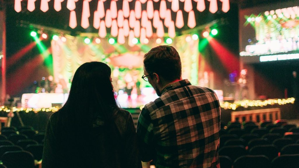 Couple watching a brightly lit stage from their seats