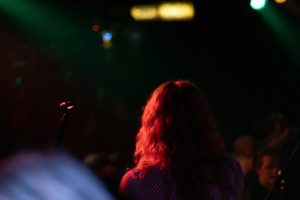 A concertgoer watching a live show under red and green stage lights