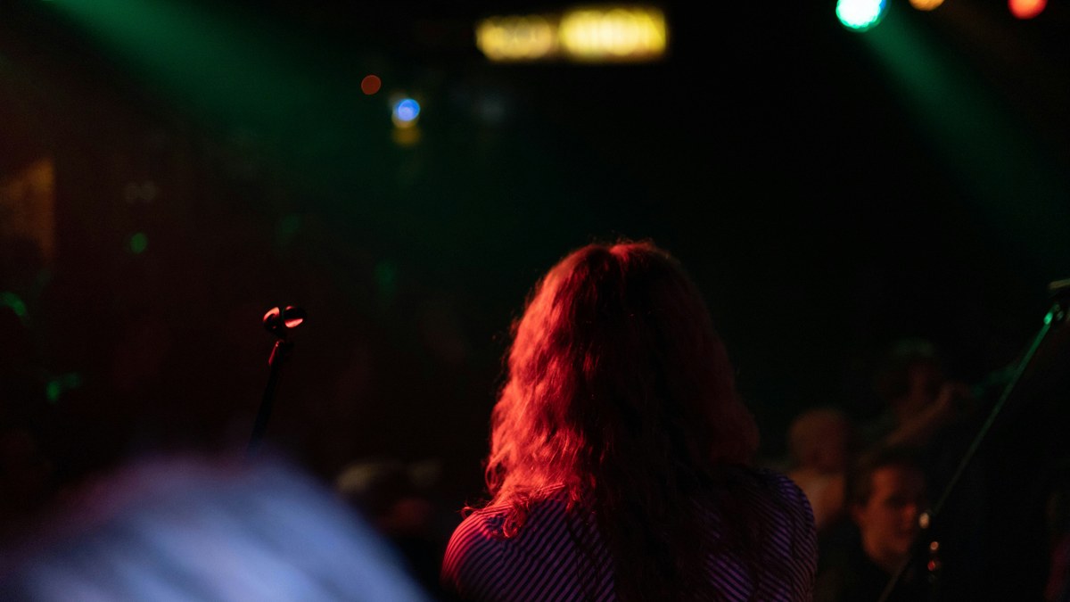 A concertgoer watching a live show under red and green stage lights