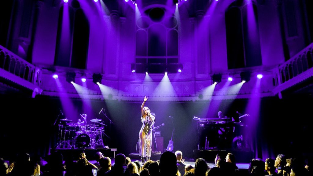 A singer performing in a grand theater with purple stage lighting