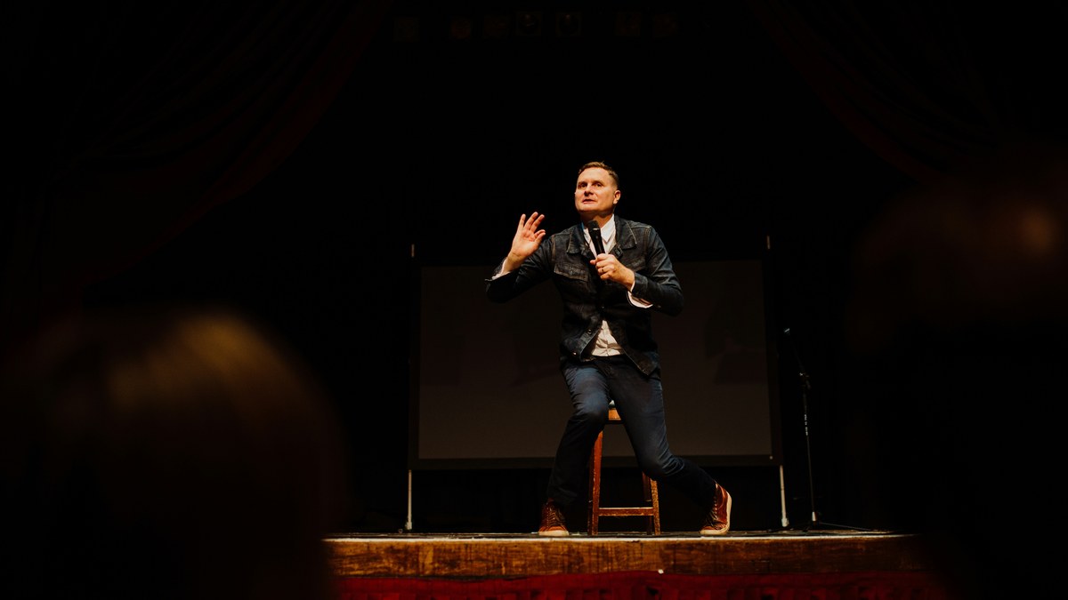 Comedian performing on stage with a microphone